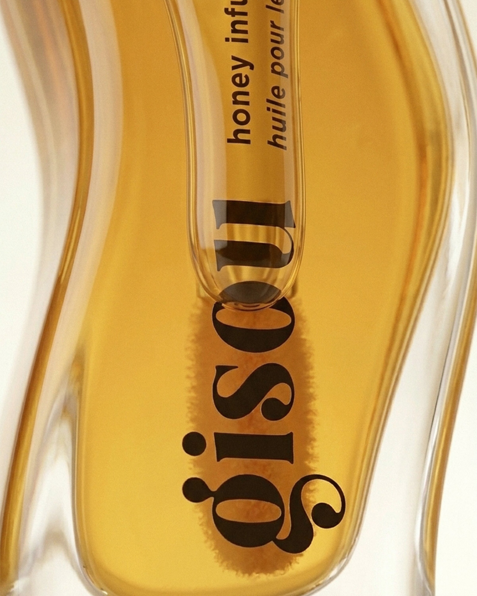 Gisou — logo macro through amber oil